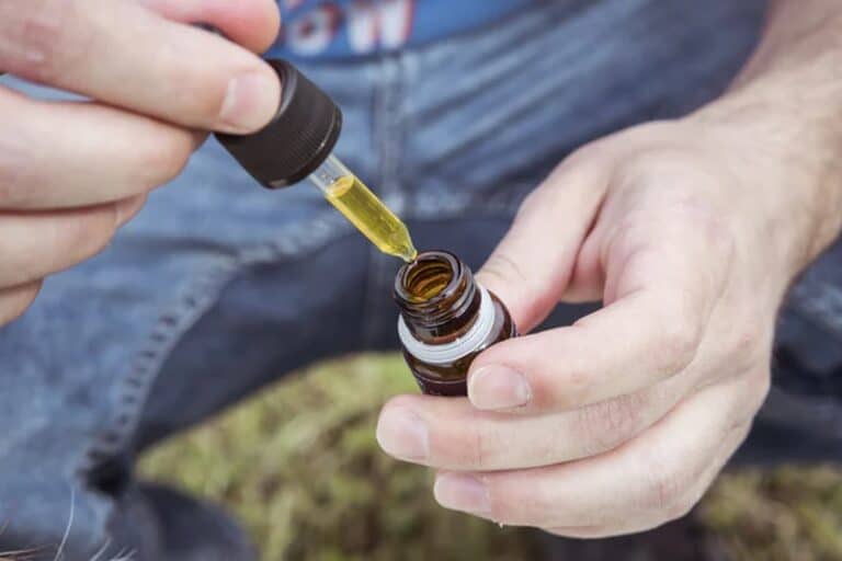 Man taking a dropper full of CBD oil to place under his tongue.