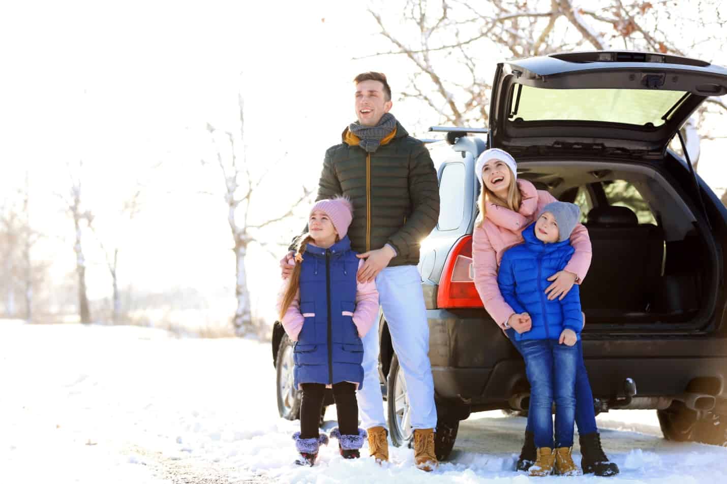 family near snowy car