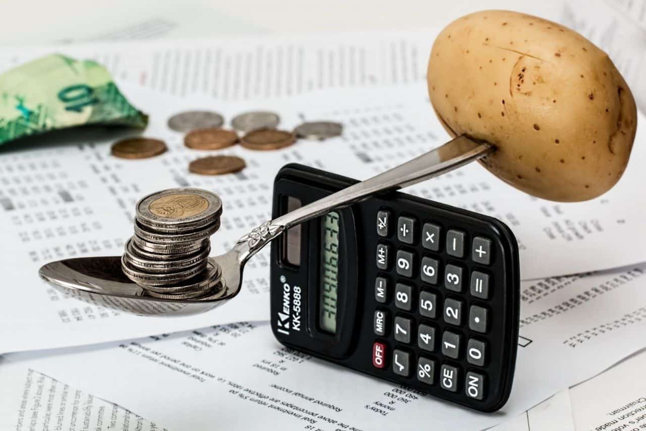 coins on spoon with potato and calculator