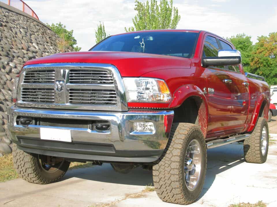 A focused man loads construction tools into a heavy-duty truck, showcasing his rugged attire and diligent work ethic. Ram 2500 3