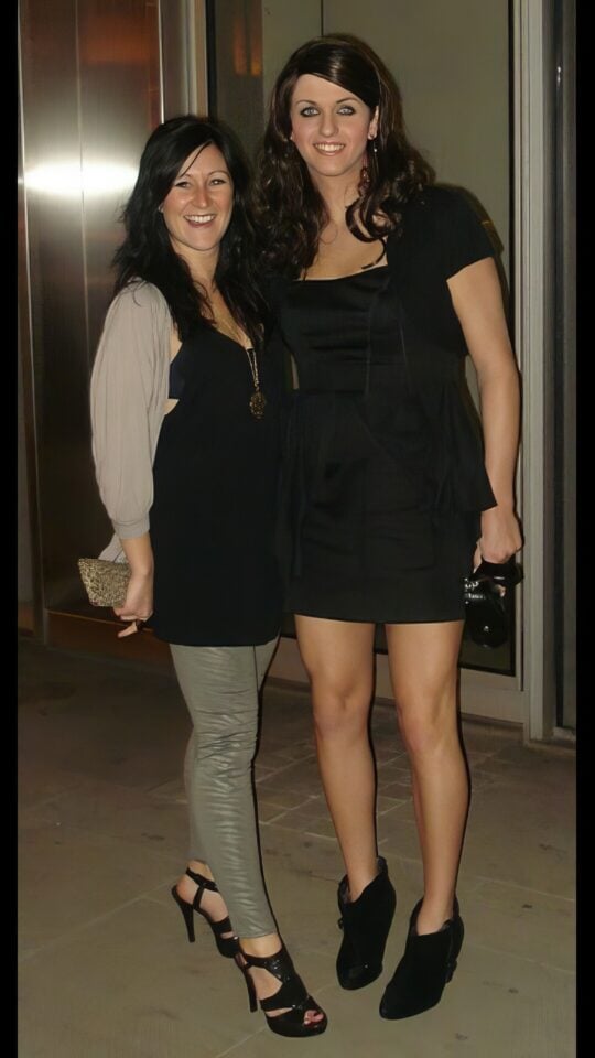 Elegant women standing together at an indoor event, dressed in stylish black dresses, showcasing friendship and fashion, perfect for nightlife or cocktail party themes.