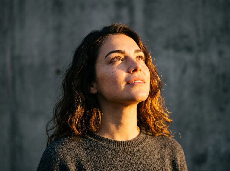 Woman with curly hair looking up with a peaceful expression, symbolizing finding joy and hope during emotional numbness, inspired by the post "How to Find Joy Each Day When You Feel Numb.".
