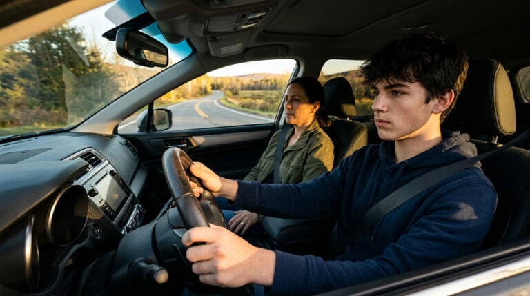 Teen driver practicing driving skills with a permit in Nevada, sitting in the driver's seat of a car on a scenic rural road during daylight.