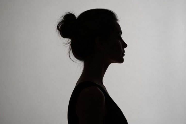 Silhouette of a woman with her hair in a bun, facing sideways against a light background, emphasizing calmness and mindfulness. Perfect for content related to mental health, wellness, and self-care.