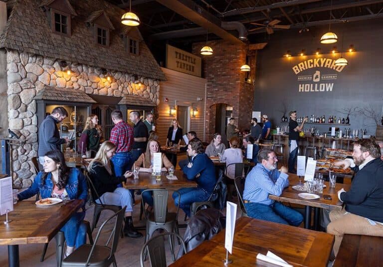 Customers enjoying food and drinks at Brickyard Hollow Brewing Company in Portland, with a lively atmosphere and rustic decor.