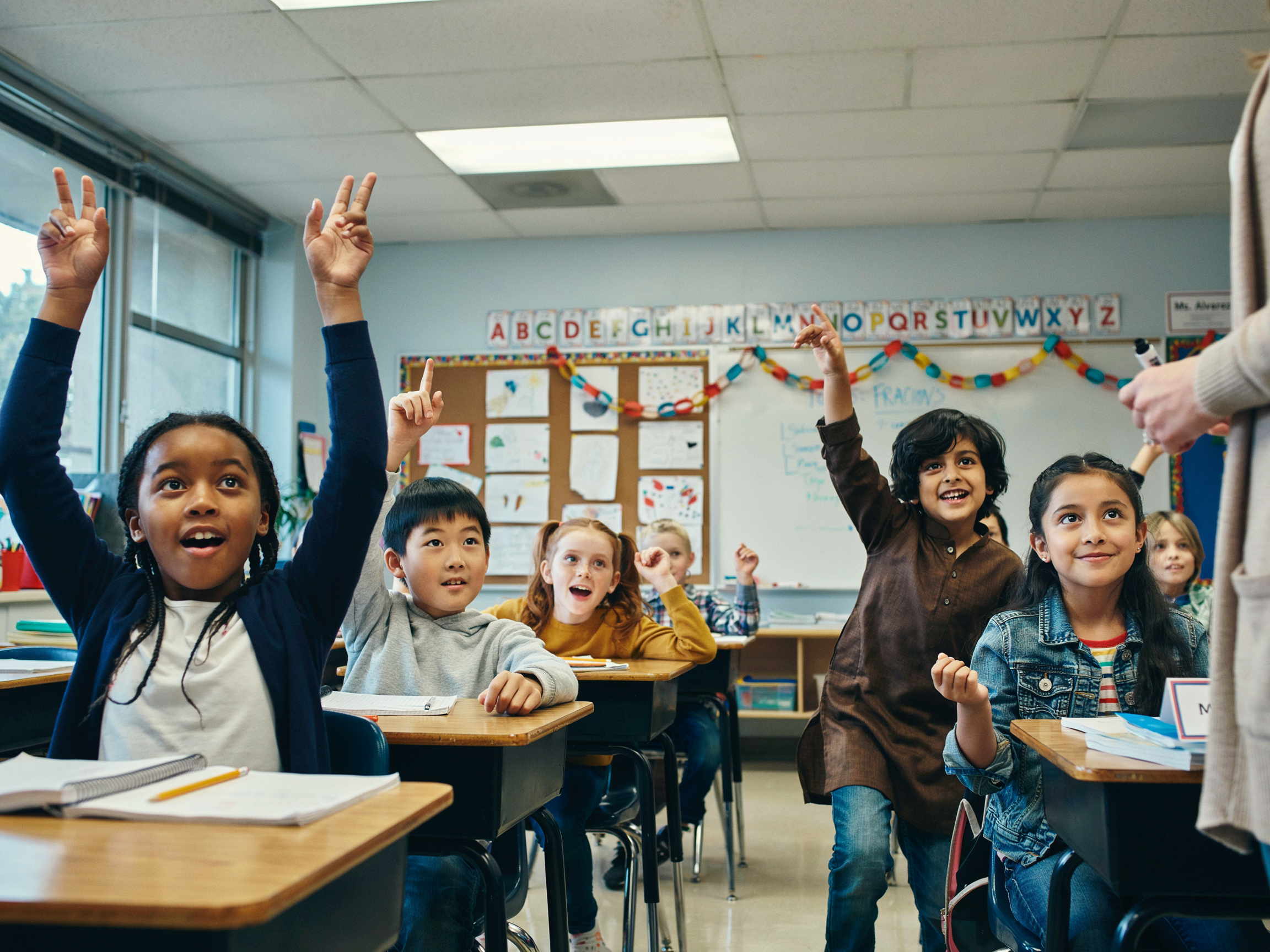 What Is the Value of Family in Sociology? A Data-Driven Look at How Families Transmit Values 5 Children raising hands in a classroom, representing the cognitive component of value learning.