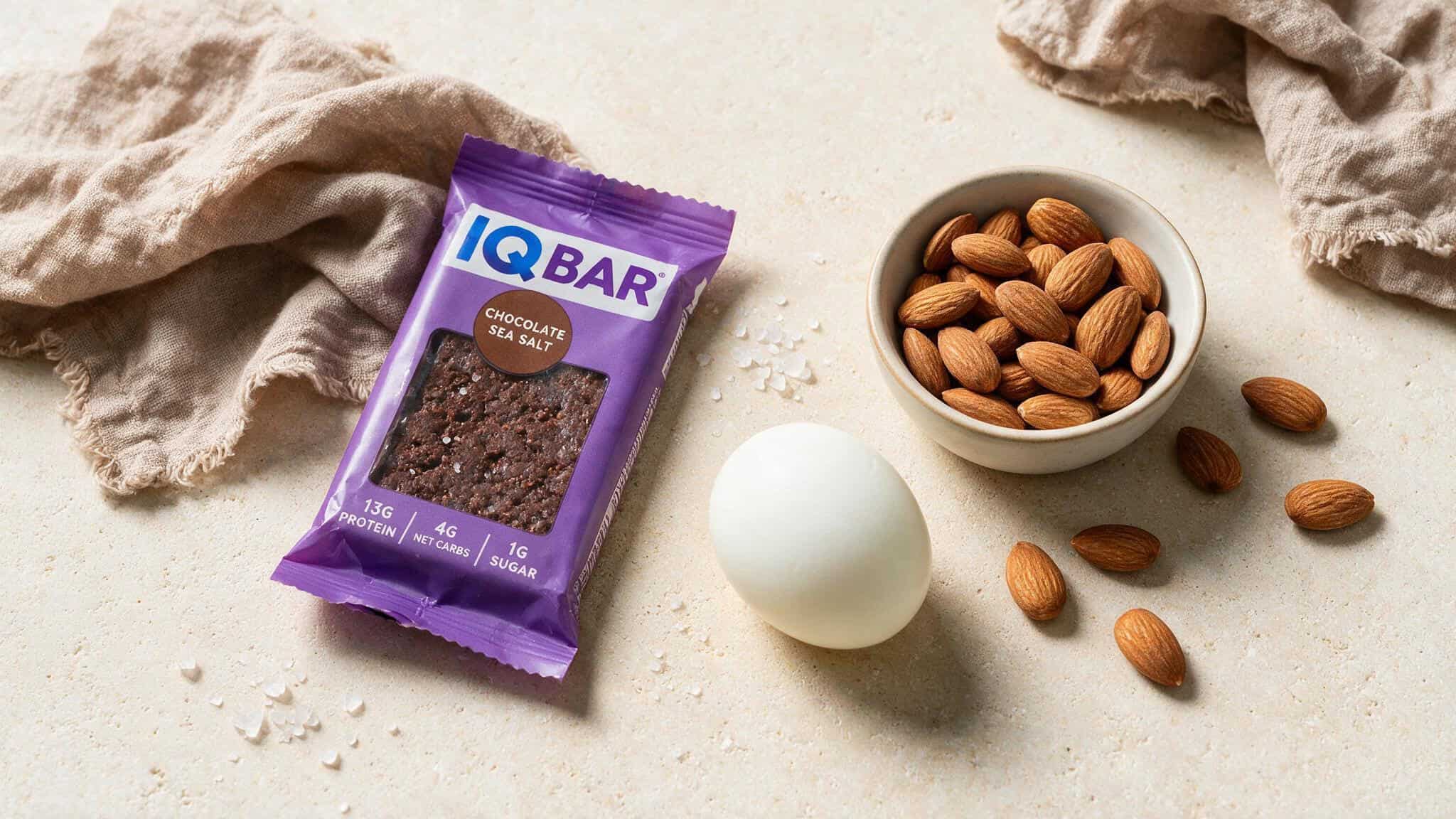 Are IQ Bars Safe to Eat Every Day? A Dietitian's 75/100 Score and the Truth About Brain Nutrients 2 IQ Bar next to hard-boiled egg and almonds, comparing protein content for snack nutrition.