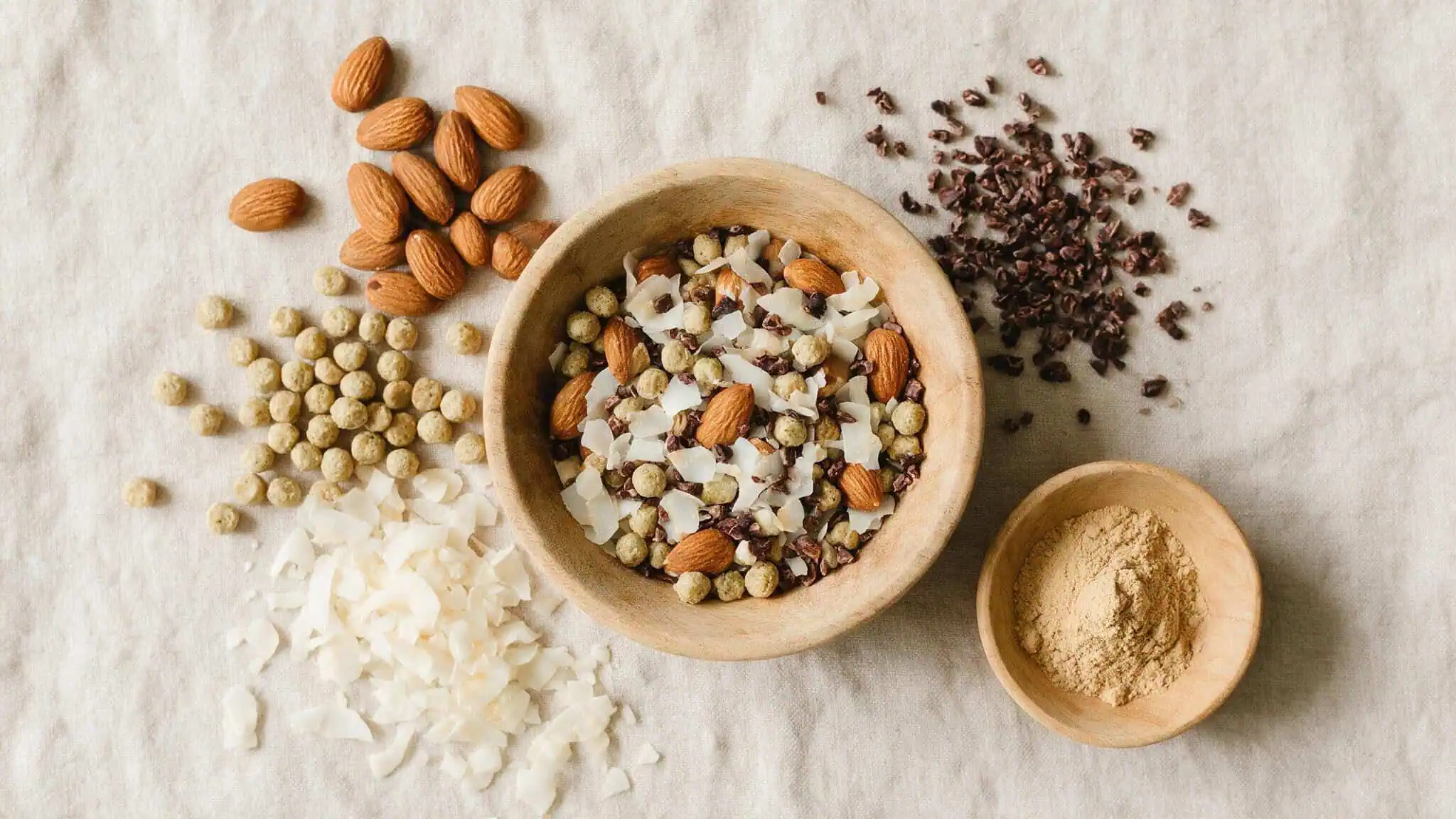 Flat lay of IQBAR ingredients including almonds, pea protein, coconut, cocoa, and Lion's Mane mushroom powder