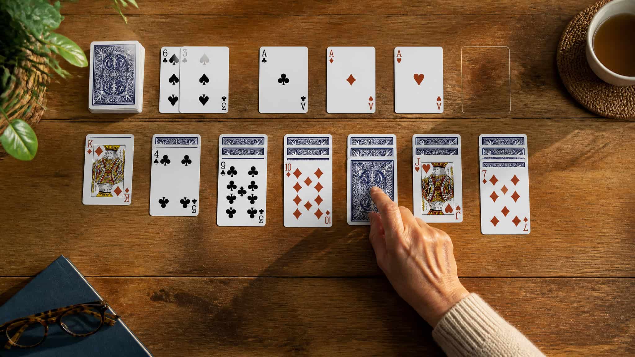 Is Solitaire a Game of Skill or Luck? The 70/30 Split 2 Hand flipping a face-down card in a solitaire game, highlighting the strategic choice to reveal hidden cards.