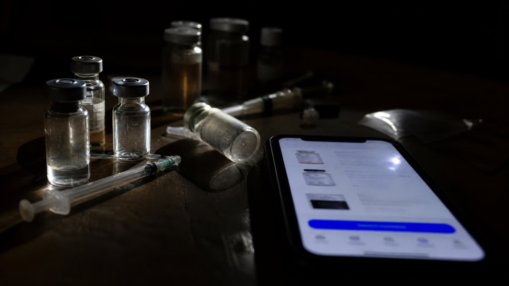 Are Weight Loss Injections Safe? What the FDA's 990 Compounded-Semaglutide Reports Show 3 Vials of vaccines and a smartphone displaying a health app, representing medical vaccination and digital health tracking.