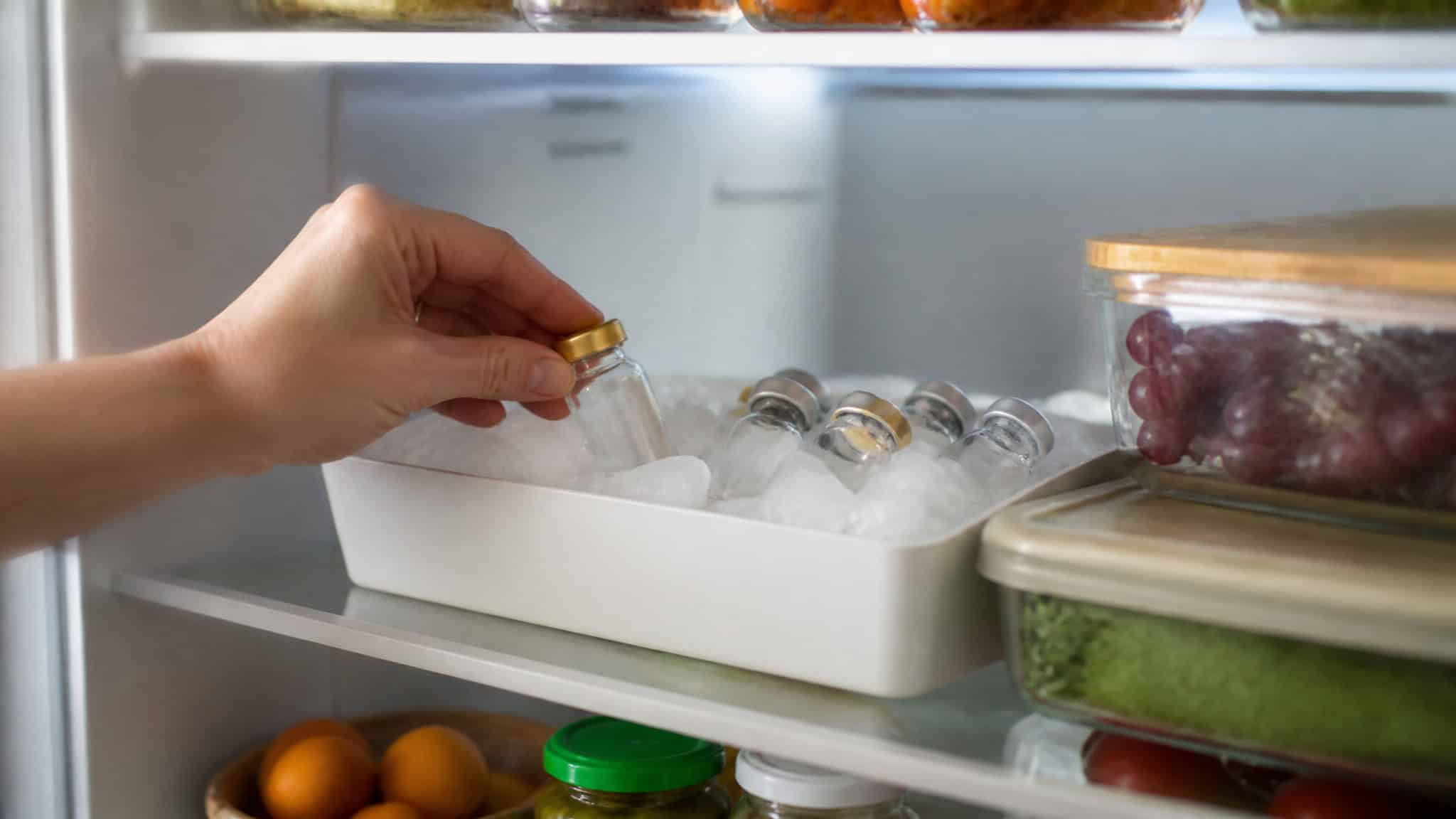 Are Weight Loss Injections Safe? What the FDA's 990 Compounded-Semaglutide Reports Show 4 Hand placing a jar into a refrigerator's chilled food storage area, with other jars and food containers visible.
