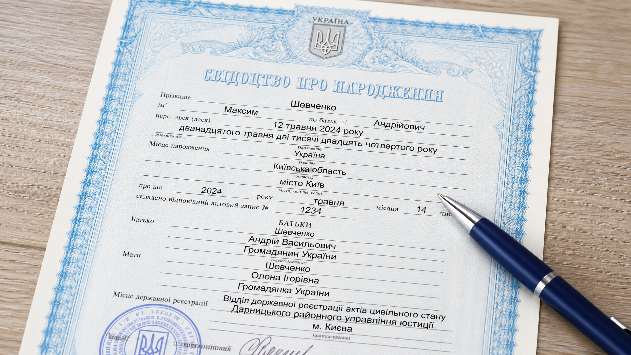 Surrogacy in Ukraine Success Stories: From 8 Failed IVF Attempts to Twins 2 Ukrainian birth certificate with personal details, official stamps, and signatures, placed on a wooden surface with a blue pen.
